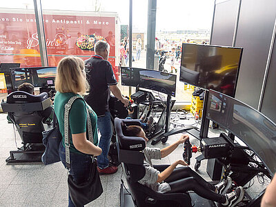 Teilnehmer die in einem Simulator Sitzen und einige Runden fahren